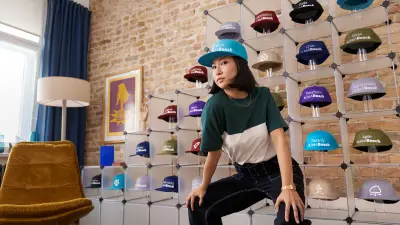 Associada em frente a um expositor cheia de bonés com gravuras relacionadas com a Bosch, como Work