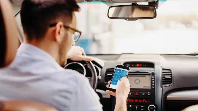 um homem usando o celular dentro de um carro