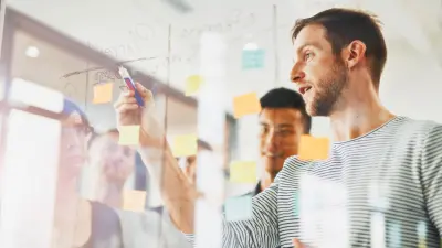 grupo de pessoas trabalhando em frente a uma lousa de vidro