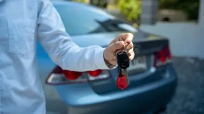 Homem segurando chave de veículo em locadora