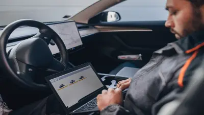 homem dentro do carro mexendo no notebook